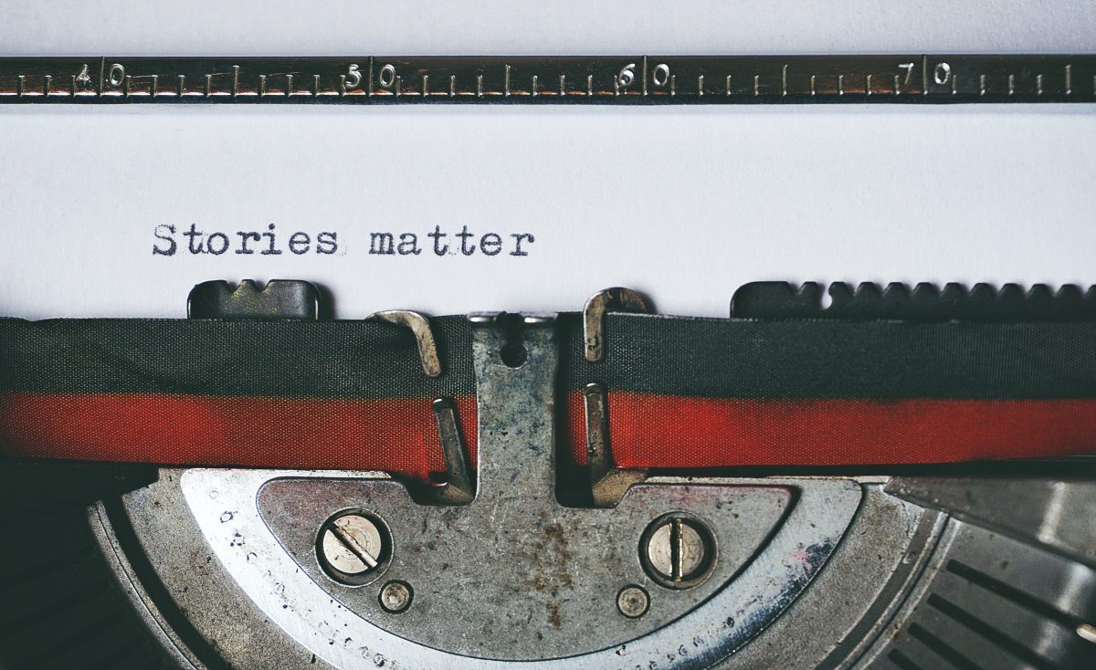 A black and red typewriter with a blank sheet of paper in the carriage